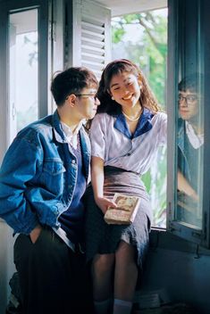 two people standing next to each other looking out the window at another person holding a book