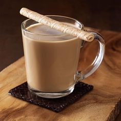 a glass mug filled with liquid and a cinnamon stick on top of the coffee cup