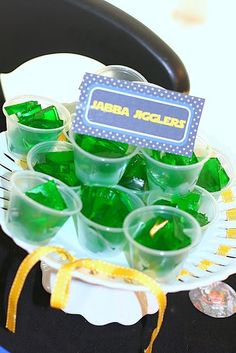 green jello cups sitting on top of a white plate next to a black chair