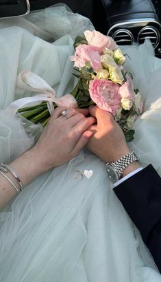 the bride and groom are holding hands on their wedding day in the back of a car