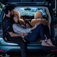 a man and woman sitting in the back of a car