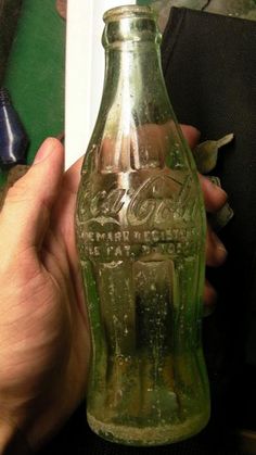 a person holding an old coca - cola bottle in their hand