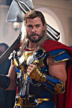 a man dressed as thor is holding two large axes in his hand and looking at the camera