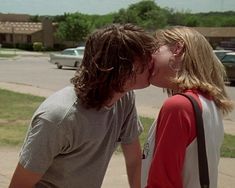 two people kissing each other on the sidewalk