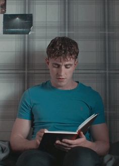 a man sitting on a bed reading a book