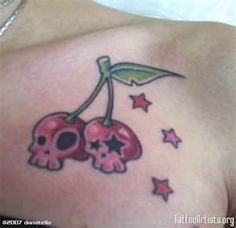 a woman's shoulder with two skulls and a cherry tattoo on her left shoulder