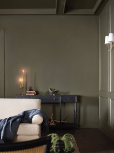 a living room with a couch, table and two candles on the wall next to it