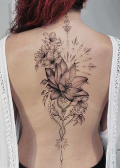 the back of a woman's body with flowers on her stomach and an arrow tattoo