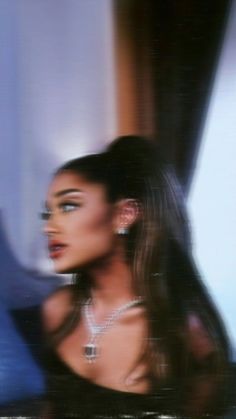 a blurry photo of a woman with long hair and jewelry on her neck, looking off to the side