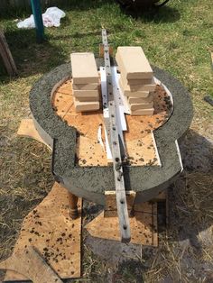 an outdoor fire pit being built in the middle of some grass and dirt with tools on it