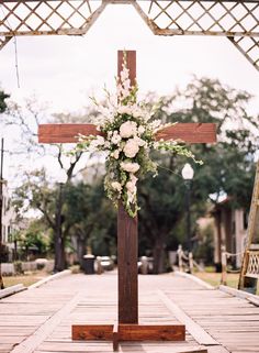 a wooden cross with white flowers on it