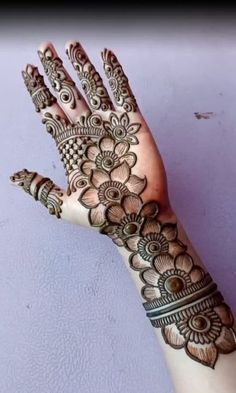 a woman's hand with henna tattoos on her arm and hands, showing the intricate