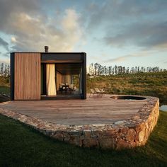 a house made out of wood and stone in the middle of a grassy area with a pool