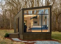 a tiny house in the middle of a forest with its windows open and lights on