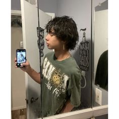 a young man taking a selfie in front of a mirror with his cell phone