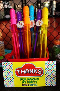 a box filled with lots of colorful pens on top of a black table next to a chain link fence