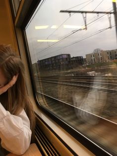 a woman sitting on a train looking out the window with her head in her hands