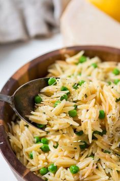 a wooden bowl filled with pasta and peas