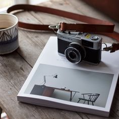 a camera sitting on top of a book next to a cup