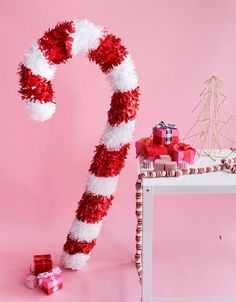 a candy cane decorated with red and white pom - poms on a pink background