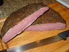 two pieces of meat sitting on top of a cutting board next to a knife