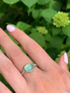 A seafoam green chrysoprase is set in 14k yellow gold a top a sterling silver seagrass band. Accented with small handmade gold beads. Approx stone size: 12mm x 10mm Approx stone weight: 2.9cts Mohs Hardness: 6-7 This one of a kind piece is handmade in Emily's Hudson Valley studio. If you have questions about sizing, shipping or need help deciding please reach out to us! Chalcedony Yellow Gold Jewelry For Anniversary, Yellow Gold Chalcedony Jewelry For Anniversary, Anniversary Yellow Gold Chalcedony Jewelry, Yellow Gold Chrysoprase Jewelry With Cabochon, Fine Jewelry In Yellow Gold With Chalcedony, Elegant Opal Ring For Healing With Natural Stones, Yellow Gold Emerald Chrysoprase Cabochon Ring, Yellow Gold Chrysoprase Cabochon Ring, Yellow Gold Rings With Chrysoprase Gemstone