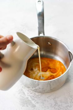 someone pouring milk into a pot filled with food