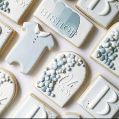 baby shower cookies are arranged in rows on a white tablecloth with blue and gold accents