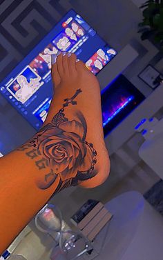 a person with a rose tattoo on their arm next to a computer monitor and keyboard