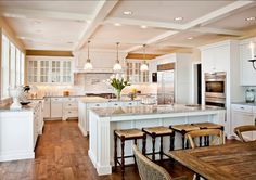 a large kitchen with white cabinets and wooden flooring, along with a center island