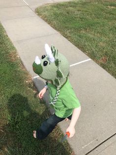 a little boy wearing a green dragon hat