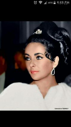 an old photo of a woman with black hair and pearls on her head, wearing a white dress