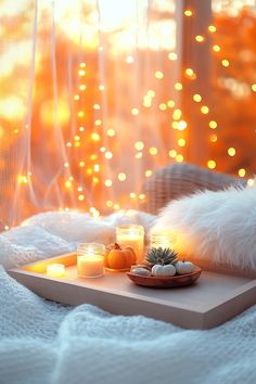 a tray with candles on top of it next to a white blanket and some lights