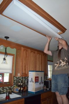 a woman standing in the middle of a kitchen holding up an object above her head