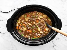 a crock pot filled with meat and vegetables on top of a marble countertop