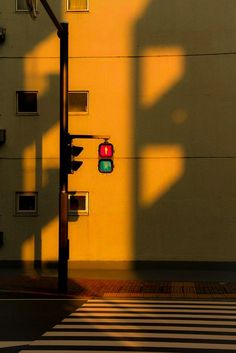 a traffic light sitting on the side of a road next to a tall yellow building