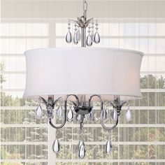 a chandelier hanging from the ceiling in front of a window with curtains behind it