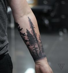 a man with a forest tattoo on his arm