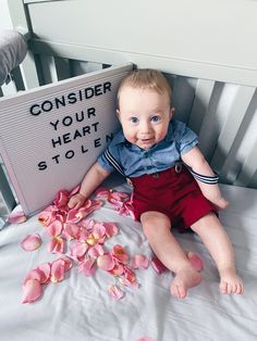 a baby sitting in a crib next to a sign that says consider your heart stolen