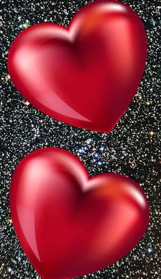 two red hearts are in the middle of a black and white background with sparkles