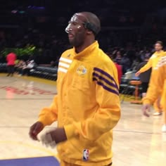 a man in yellow jacket and black shorts on basketball court