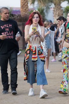 a woman with red hair is looking at her cell phone while two other people are walking behind her