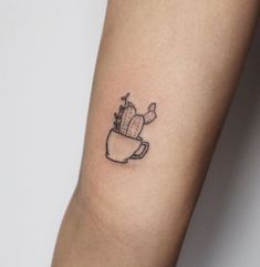 a small cactus in a cup tattoo on the arm