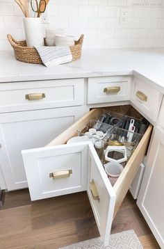 an open drawer in a white kitchen with utensils and other items inside it