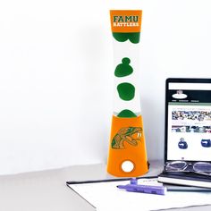 an orange and white vase sitting on top of a desk next to a laptop computer