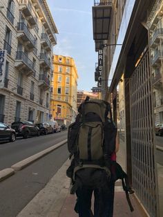 a person with a backpack is walking down the sidewalk in front of some tall buildings