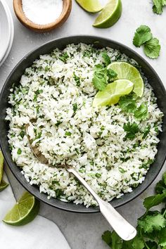 rice and cilantro in a skillet with limes on the side for garnish