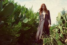 a woman standing in the middle of a cactus field