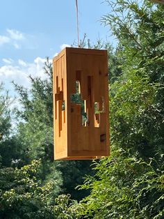 a wooden birdhouse hanging from a tree in the middle of some bushes and trees