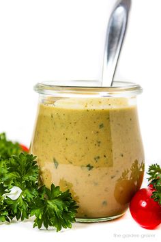 a jar filled with dressing and garnished with parsley next to fresh tomatoes